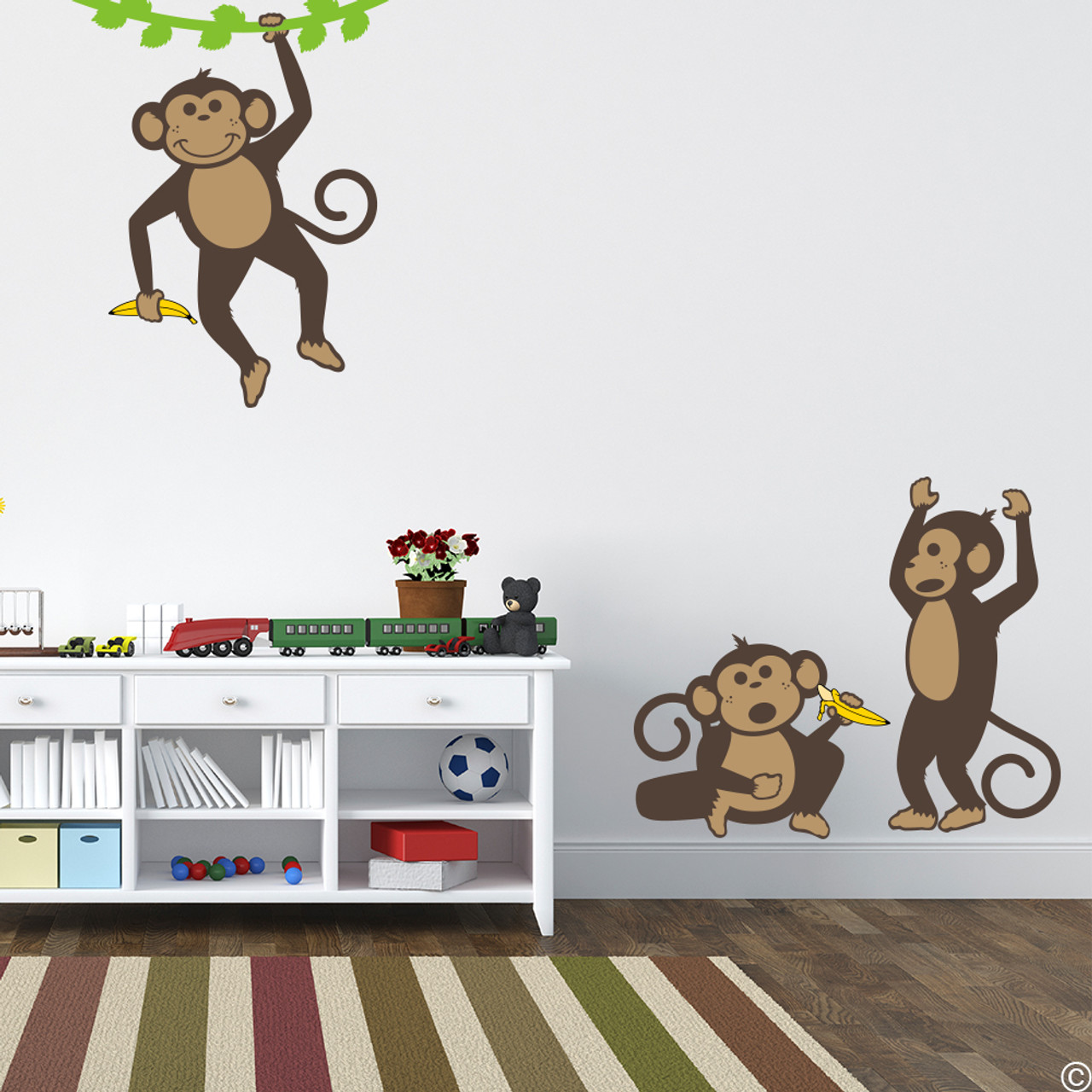 Vinyl wall decals of three monkeys holding bananas and playing .