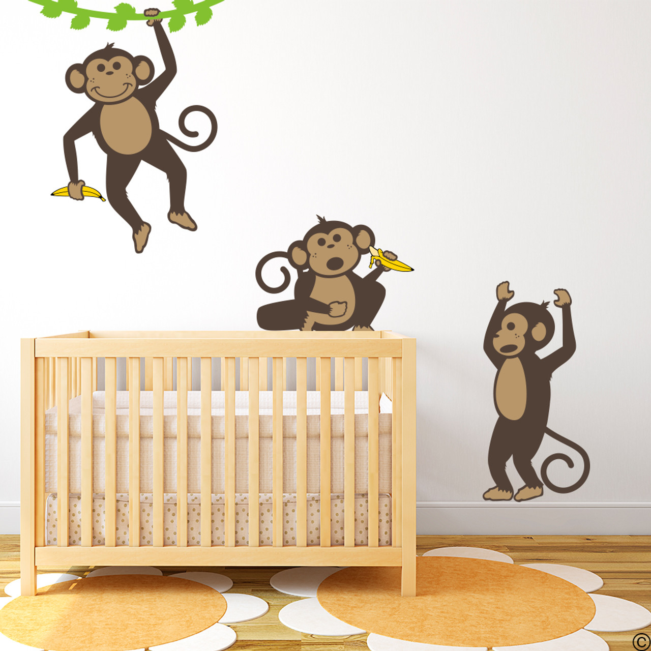 Vinyl wall decals of three monkeys holding bananas and playing .