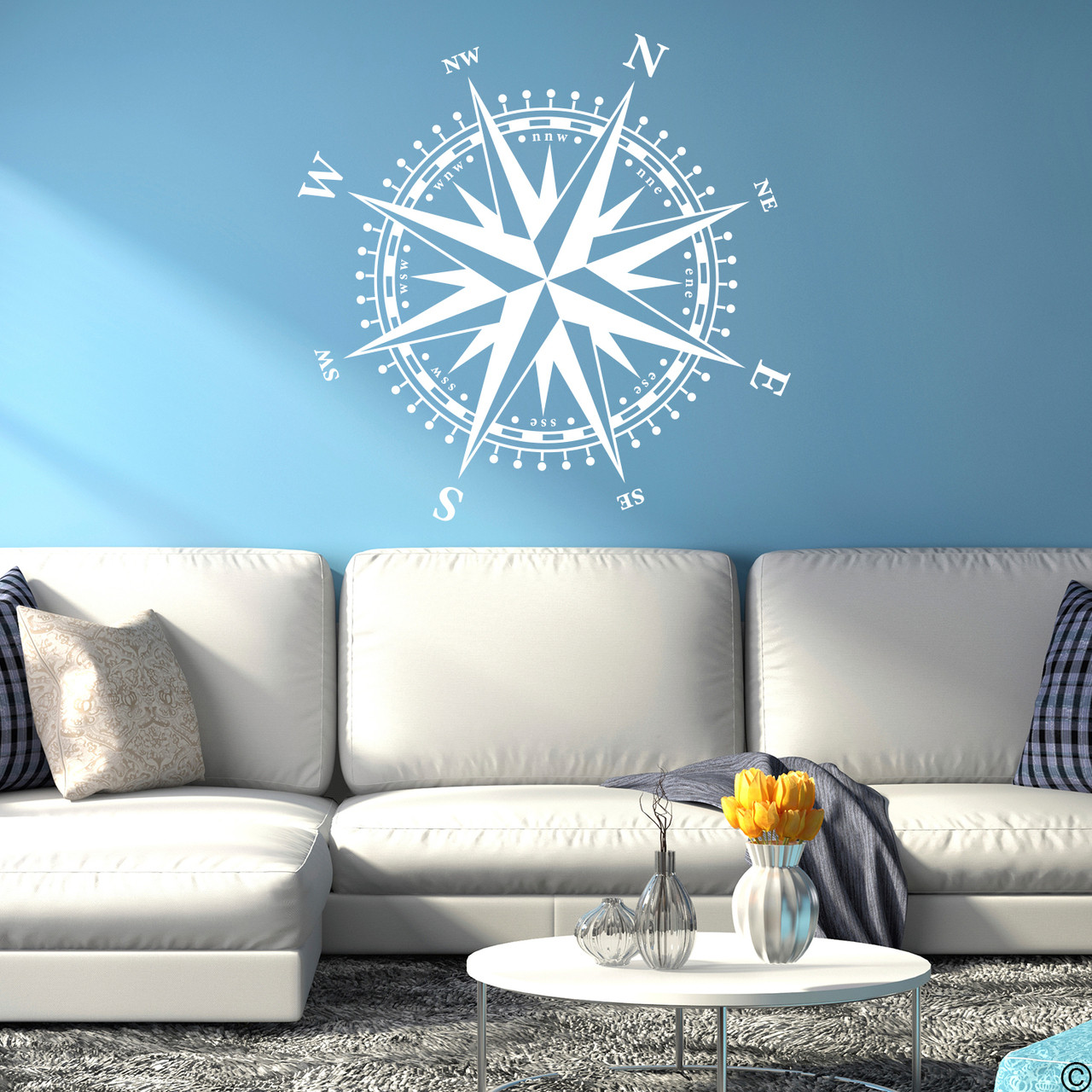 The Christopher Compass wall decal in white vinyl and placed over a couch in a living room.