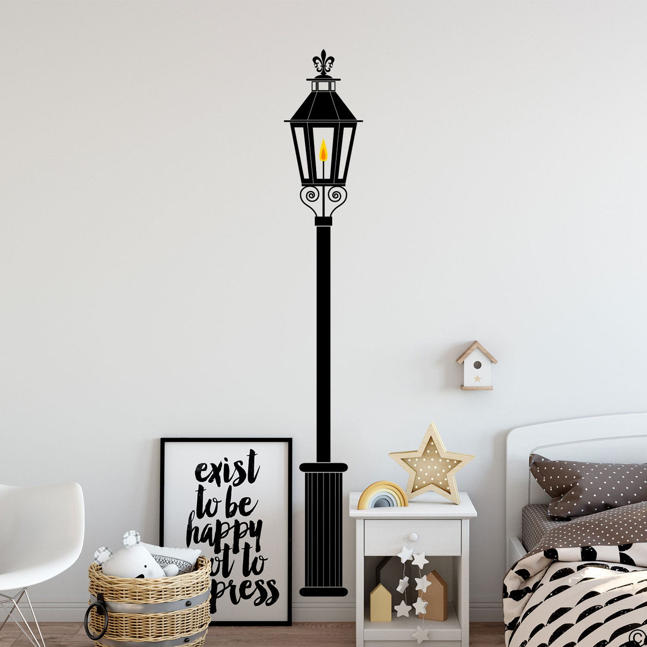 A black gas lamp wall decal with fleur-de-lys accent on a bedroom wall.