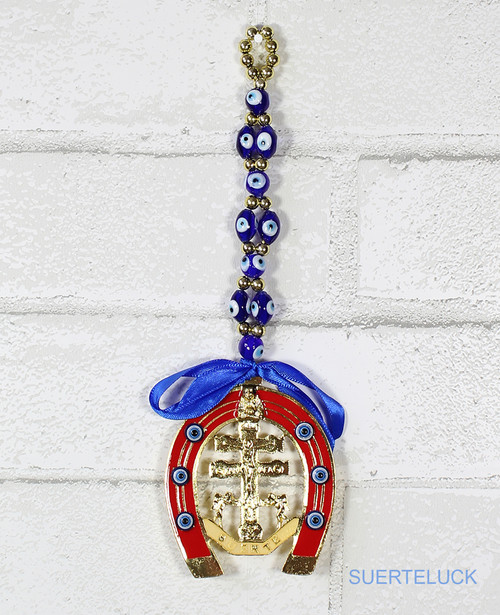 Spinning Caravaca Cross With 16 Evil Eyes hanging from a white brick wall 