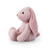 Side view of a plush pink bunny with floppy ears, soft fur, and stitched features, sitting upright.