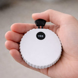 A drink bottle opener in a circular shape, predominantly white with a black lever and a "YES" indicator.