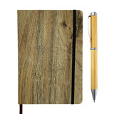 A wooden-look notebook with a black elastic band and a silver and bamboo pen beside it. The notebook has a natural texture.