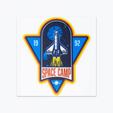 A blue and yellow sticker featuring a space shuttle design, with "SPACE CAMP" and a planet logo.