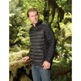 A man wearing a black thermal puffer jacket stands outdoors among lush greenery, featuring a logo on the jacket. A man wearing a black thermal puffer jacket stands outdoors among lush greenery, featuring a logo on the jacket.