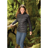 A woman wearing a black puffer jacket walks through a lush, green forest, surrounded by moss-covered trees. A woman wearing a black puffer jacket walks through a lush, green forest, surrounded by moss-covered trees.