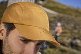 A gold cap with water droplets on the surface, featuring a logo, set against a blurred outdoor background. A gold cap with water droplets on the surface, featuring a logo, set against a blurred outdoor background.