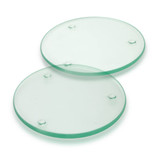 A round glass coaster set of two, featuring a light green tint and small rubber pads for stability.