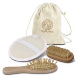 A natural beauty travel set featuring a canvas pouch, a body brush, a hairbrush, and a cleansing pad.
