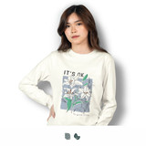 A woman wearing a long sleeve crew shirt in white, featuring floral artwork and a logo. A woman wearing a long sleeve crew shirt in white, featuring floral artwork and a logo.