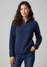 A woman wearing a navy blue polar fleece jumper with a quarter zip and a fitted design, paired with jeans.