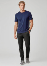 A navy short sleeve tee is worn by a model paired with black trousers and running shoes, featuring a logo on the sleeve.