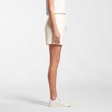 A pair of cream sports shorts with an elastic waistband and a logo on the side, displayed from the side view.