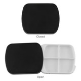 A black pill box, square-shaped, opens to reveal four compartments inside. The lid is black, while the interior is white.
