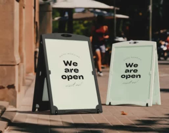 A-frame signs in black and white display the message "We are open." The signs are positioned outdoors on a pavement.