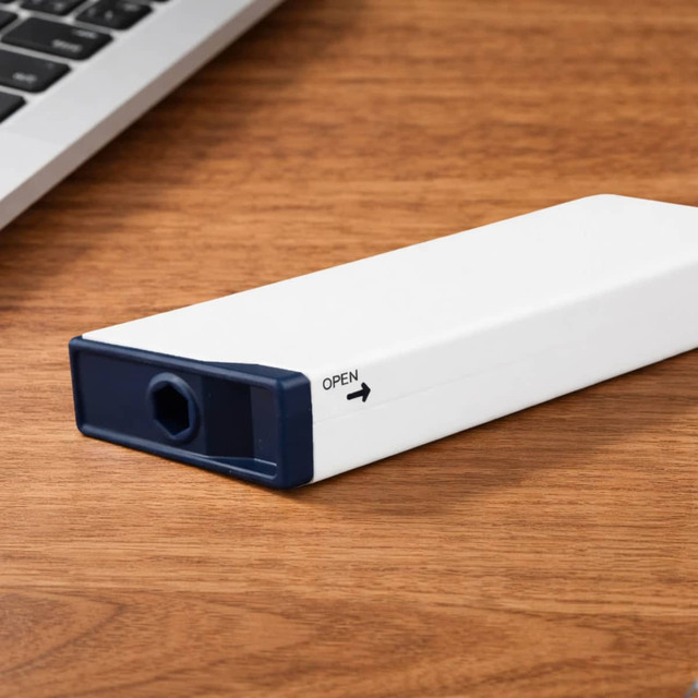 A white and navy blue screwdriver tape measure rests on a wooden surface beside a laptop.