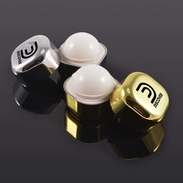 Two lip balm containers, one clear and one gold, featuring rounded white balm. Each has a logo on the lid. Two lip balm containers, one clear and one gold, featuring rounded white balm. Each has a logo on the lid.