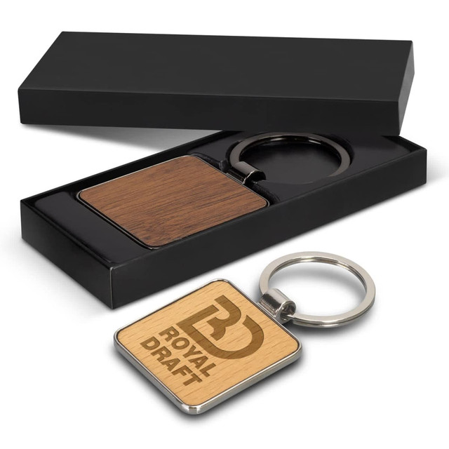 A square wooden key ring with a metallic keychain, presented in a sleek black box. A square wooden key ring with a metallic keychain, presented in a sleek black box.