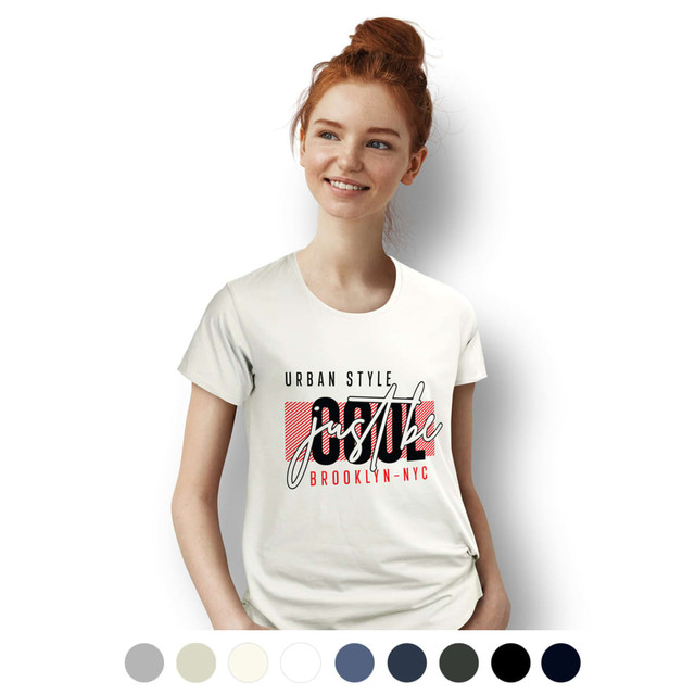 A white women's T-shirt with a graphic design featuring urban style text. The model has red hair and is smiling.