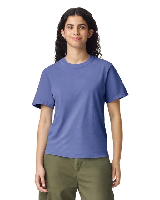 A woman wearing a purple t-shirt with short sleeves, paired with green pants. The shirt features a logo.