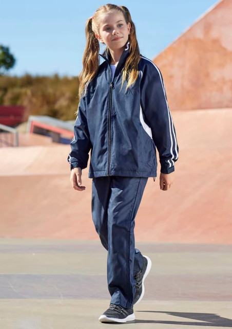 A girl walks in navy blue track pants with white stripes, paired with a matching jacket and sneakers. A girl walks in navy blue track pants with white stripes, paired with a matching jacket and sneakers.