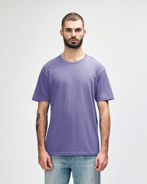 A purple Gildan Softstyle adult midweight T-shirt displayed on a model, featuring a logo on the chest.