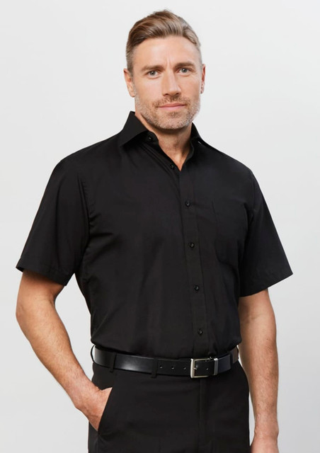 A black short-sleeve button-up shirt worn by a man, featuring a collar and buttons. It has a logo on it.