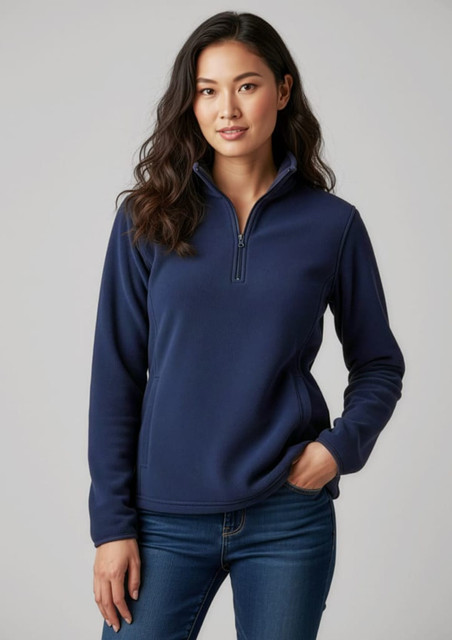 A woman wearing a navy blue polar fleece jumper with a quarter zip and a fitted design, paired with jeans.