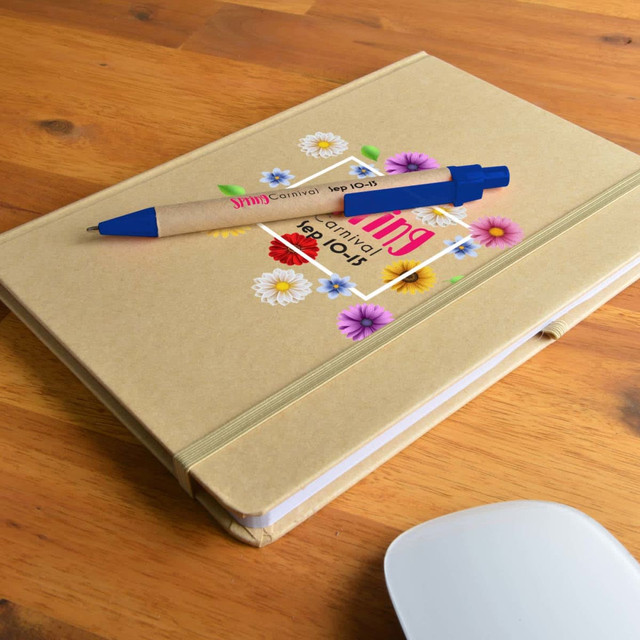 A tan A5 notebook with floral designs and a blue pen resting on top, placed on a wooden surface. A tan A5 notebook with floral designs and a blue pen resting on top, placed on a wooden surface.