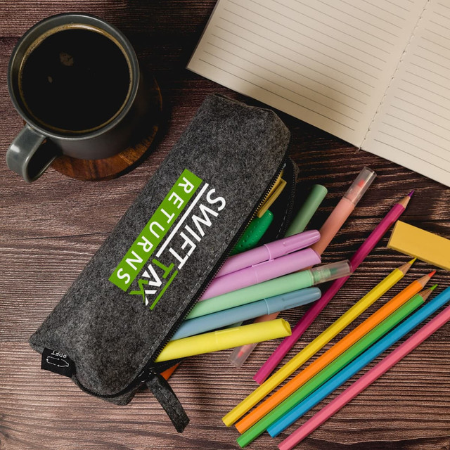 A grey felt utility case filled with colourful pens and markers, alongside a cup of coffee and a notebook. A grey felt utility case filled with colourful pens and markers, alongside a cup of coffee and a notebook.