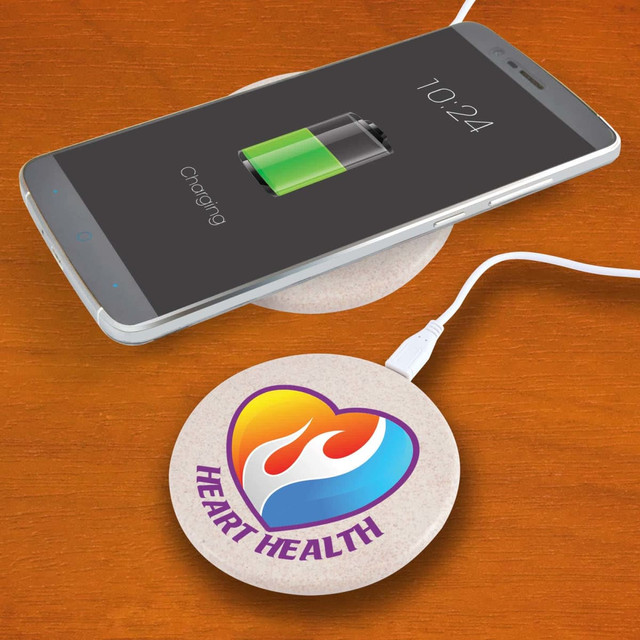 A round, natural-coloured wireless charger sits on a wooden surface next to a smartphone displaying a charging battery icon. A round, natural-coloured wireless charger sits on a wooden surface next to a smartphone displaying a charging battery icon.