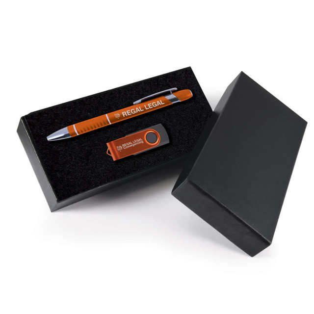 A black gift box containing an orange pen and an orange USB drive, both featuring branding. A black gift box containing an orange pen and an orange USB drive, both featuring branding.