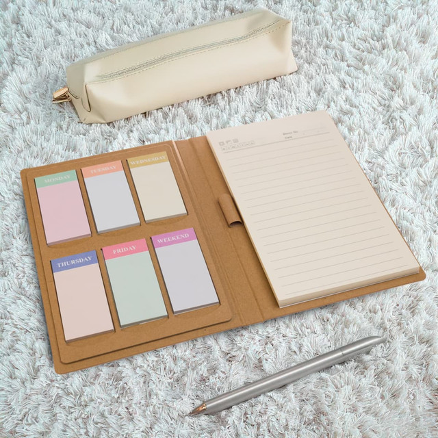 A Daily Note Planner with a brown cover, featuring pastel sticky notes, a cream pencil case, and a silver pen. A Daily Note Planner with a brown cover, featuring pastel sticky notes, a cream pencil case, and a silver pen.