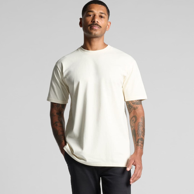 A plain cream short-sleeve T-shirt on a man, showcasing a relaxed fit. The shirt features a logo on the front. A plain cream short-sleeve T-shirt on a man, showcasing a relaxed fit. The shirt features a logo on the front.
