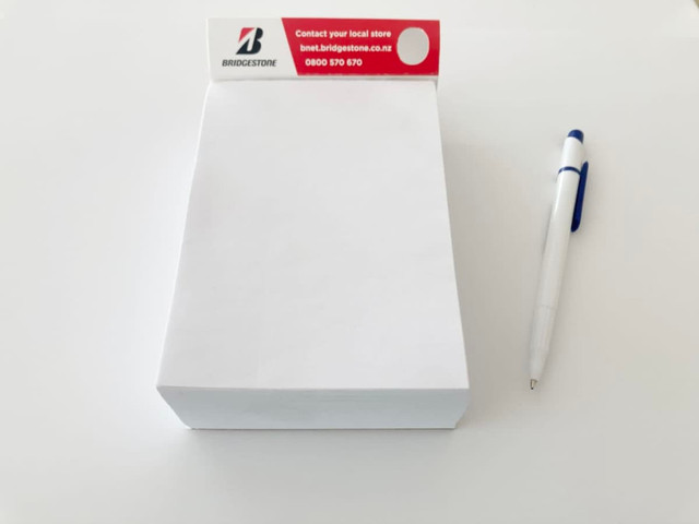 A large white notepad with a red and white header and a blue pen resting beside it. A large white notepad with a red and white header and a blue pen resting beside it.