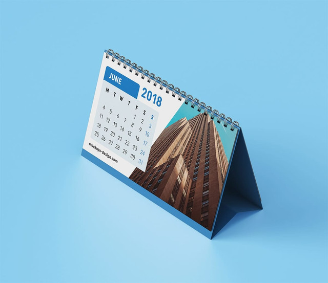 A desk calendar with a blue base, featuring a skyscraper image and a June 2018 calendar layout. A desk calendar with a blue base, featuring a skyscraper image and a June 2018 calendar layout.