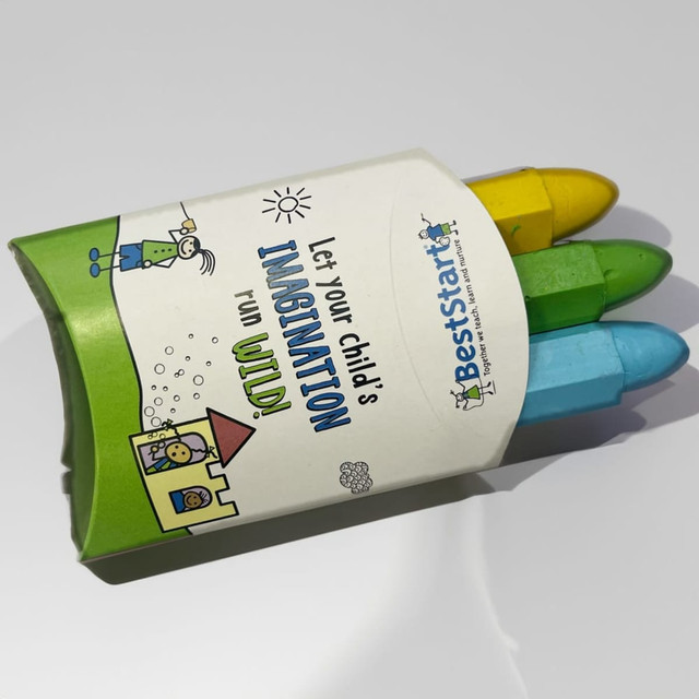 A pack of three crayons in yellow, green, and blue, packaged in a brightly designed cardboard holder with a logo. A pack of three crayons in yellow, green, and blue, packaged in a brightly designed cardboard holder with a logo.