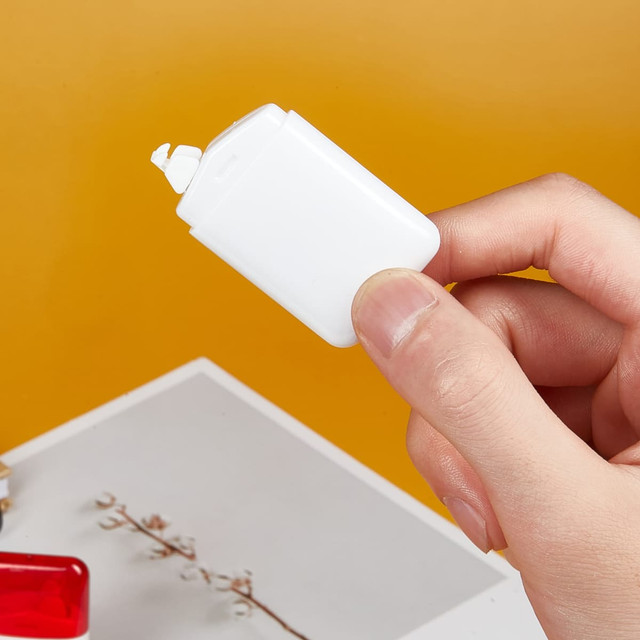A white correction tape dispenser held in a hand, set against a bright yellow background.