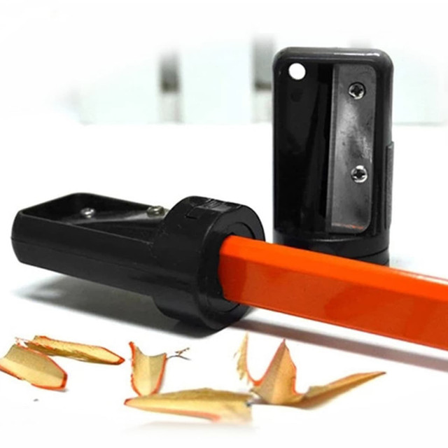A carpenter pencil sharpener in black and orange, featuring shavings on a surface beside it.