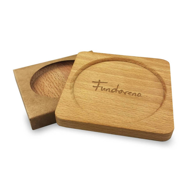 A wooden coaster in a natural finish, featuring a circular indentation and a branded logo, presented with its packaging.
