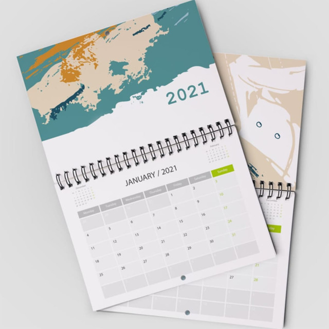 A wall calendar featuring a spiral binding, with abstract designs in teal, orange, and beige for January 2021.
