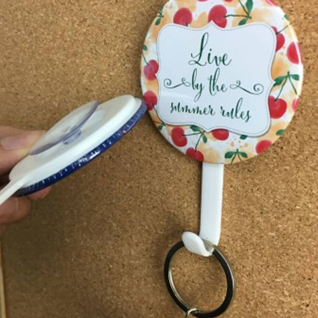 A round button badge with a colourful fruit design and a white clip attached to a keyring.