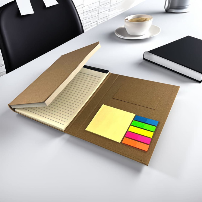 A brown memo stationery set featuring a lined notebook and colourful sticky notes, displayed on a desk with a chair and cup.