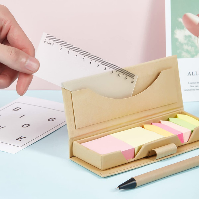 A memo holder in beige housing various sticky notes in pastel colours, accompanied by a ruler and a pen on a light blue surface.