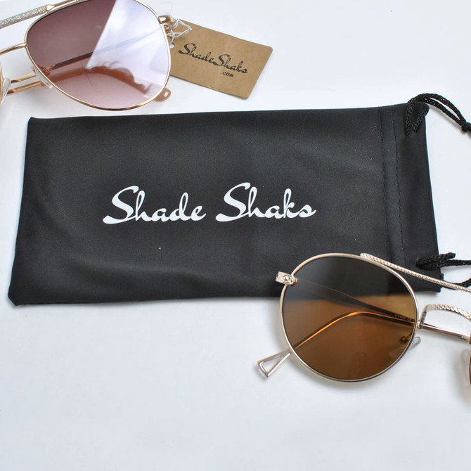 A black microfiber pouch with a logo, accompanied by brown-tinted sunglasses.