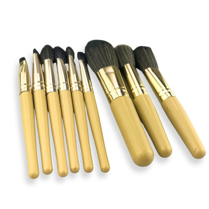 A set of nine makeup brushes with gold and beige handles, arranged in a case.