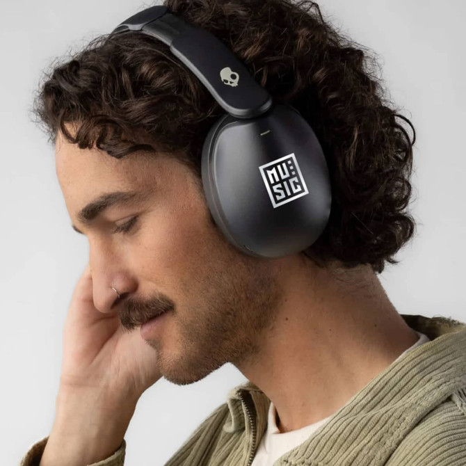 A pair of black Skullcandy Hesh 360 headphones worn by a man with curly hair, showcasing a sleek design.