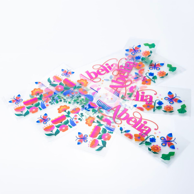 A collection of colourful stickers featuring floral designs and butterflies on a white background, with a logo present.