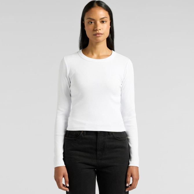 A woman wearing a white long-sleeve tee paired with black jeans, featuring a logo on the side.
